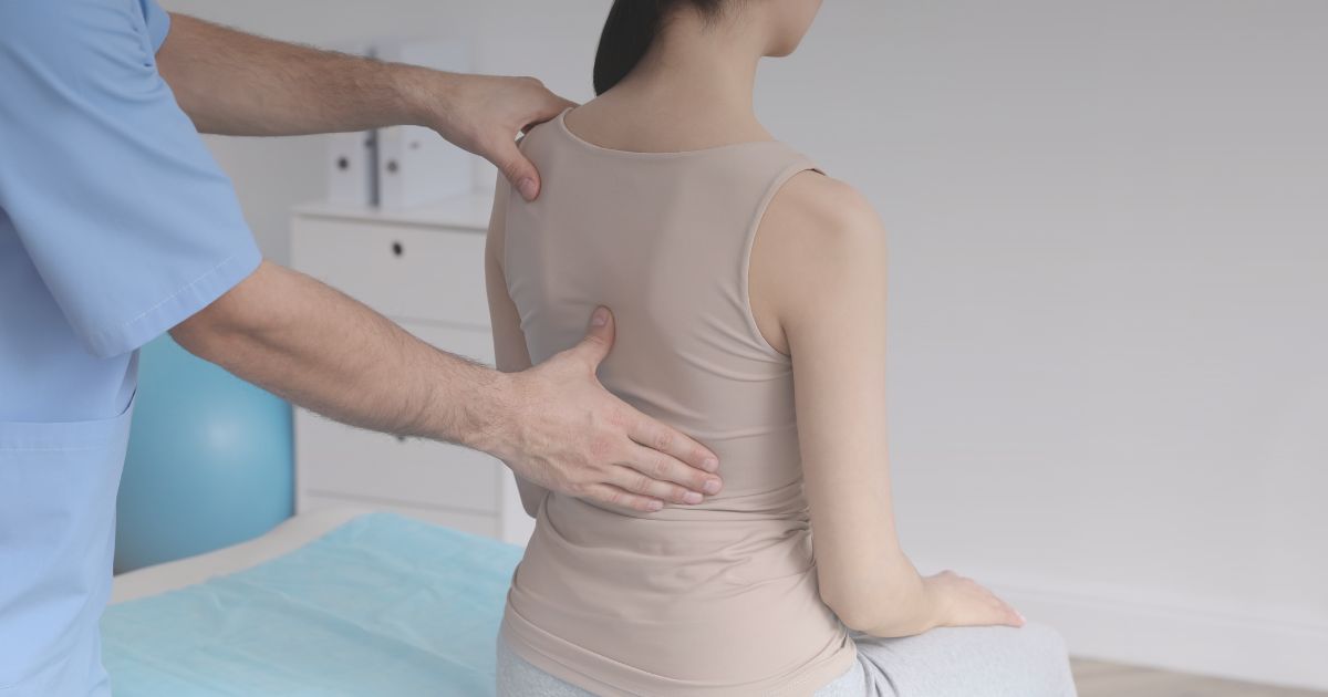 Medical professional examining patient's back during chiropractic or physiotherapy session