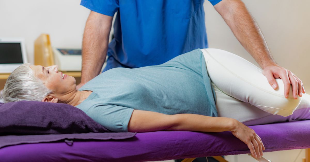 Physical therapist treating patient with pillow support on examination table