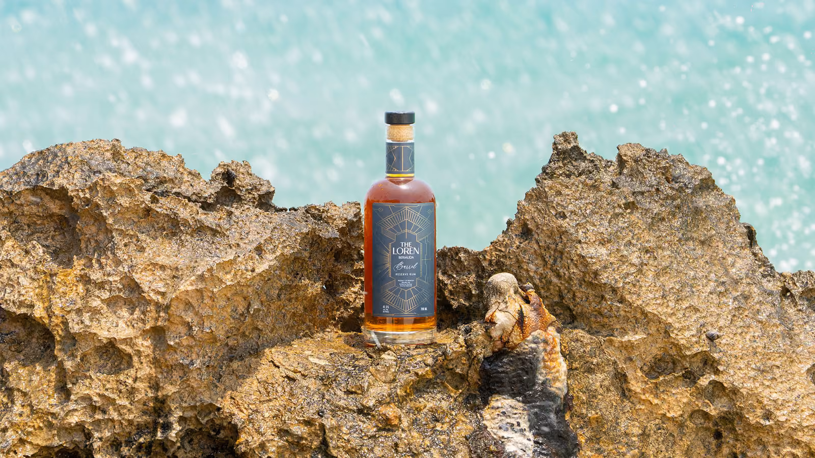 Hand holding tray with bottle of Loren Bermuda rum and two cocktails with garnishes.