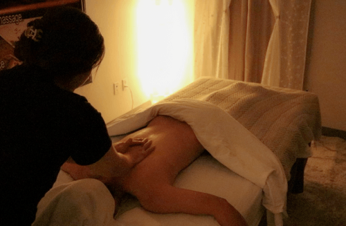 A massage therapist shown from behind giving a professional massage.