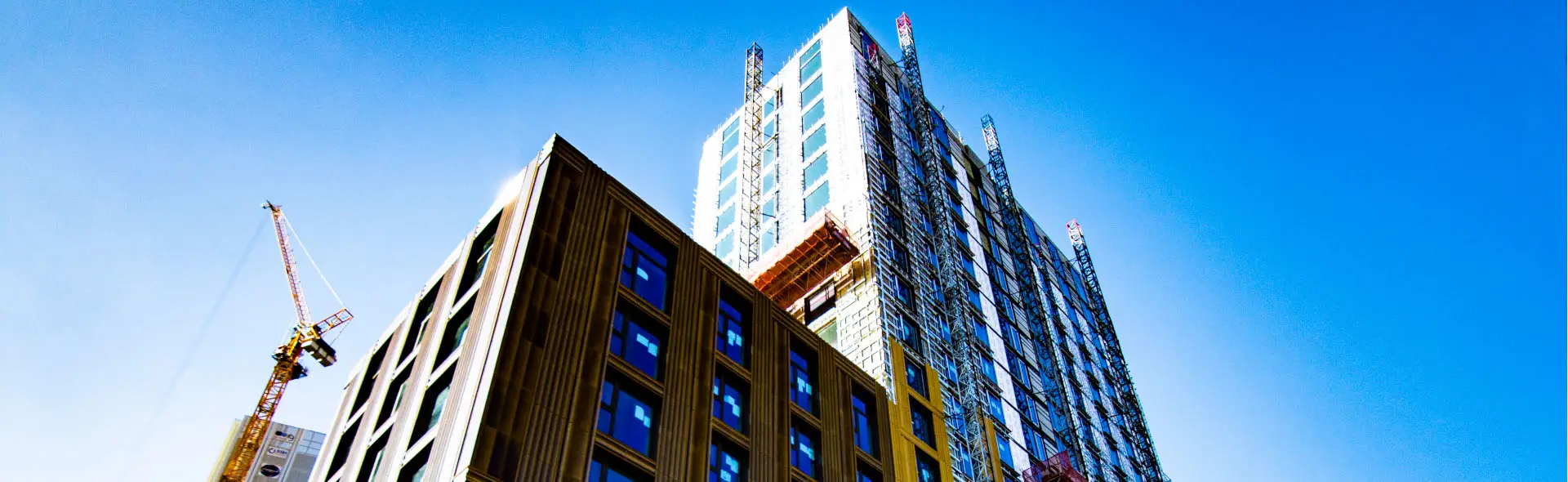 High-rise under construction with scaffolding and a crane