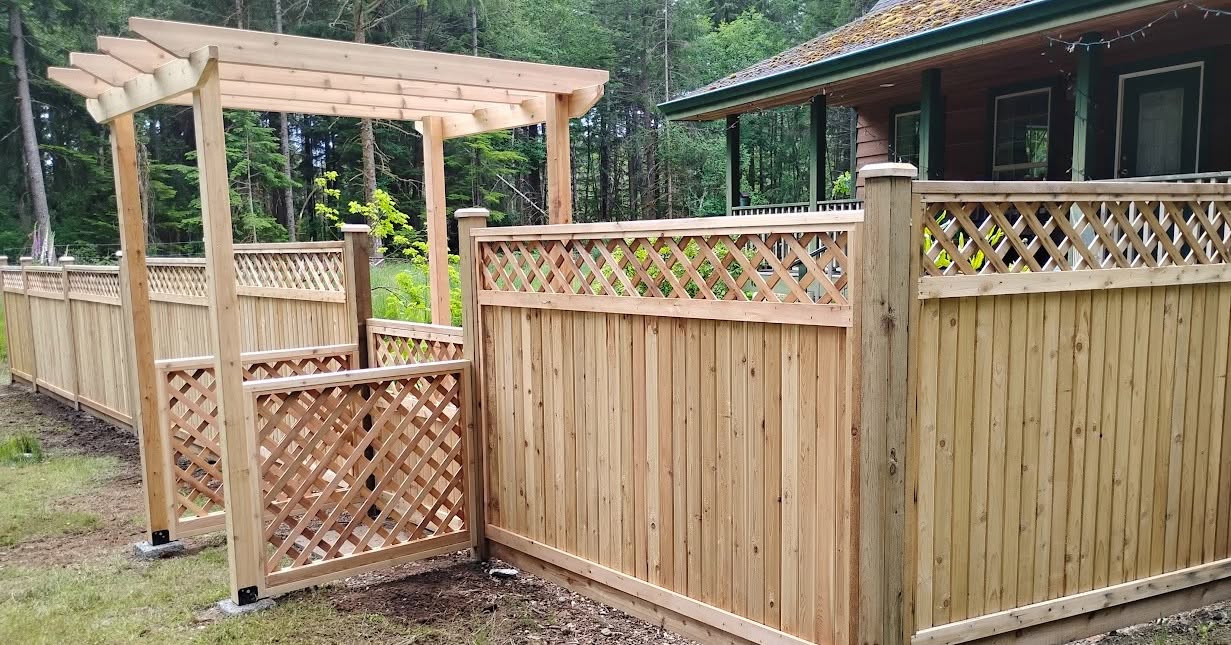 Cedar privacy fence with lattice panels, a matching gate and a timber arbor beside a house.