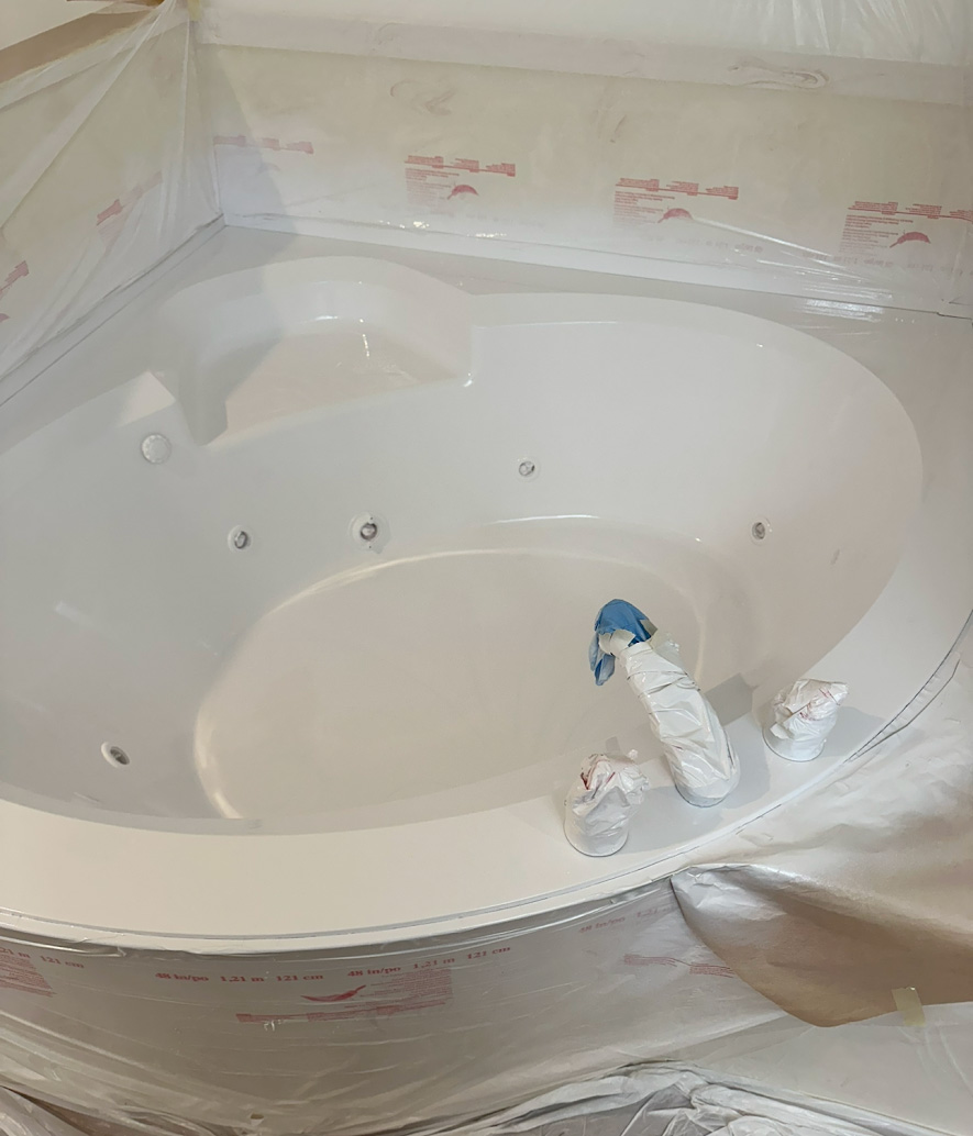 White corner jacuzzi bathtub covered with protective plastic wrap during installation or renovation.