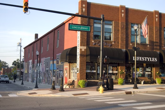 Corner of a brick building with black awnings and 'Lifestyles' signage at Lincolnway street intersection with a traffic light showing yellow.