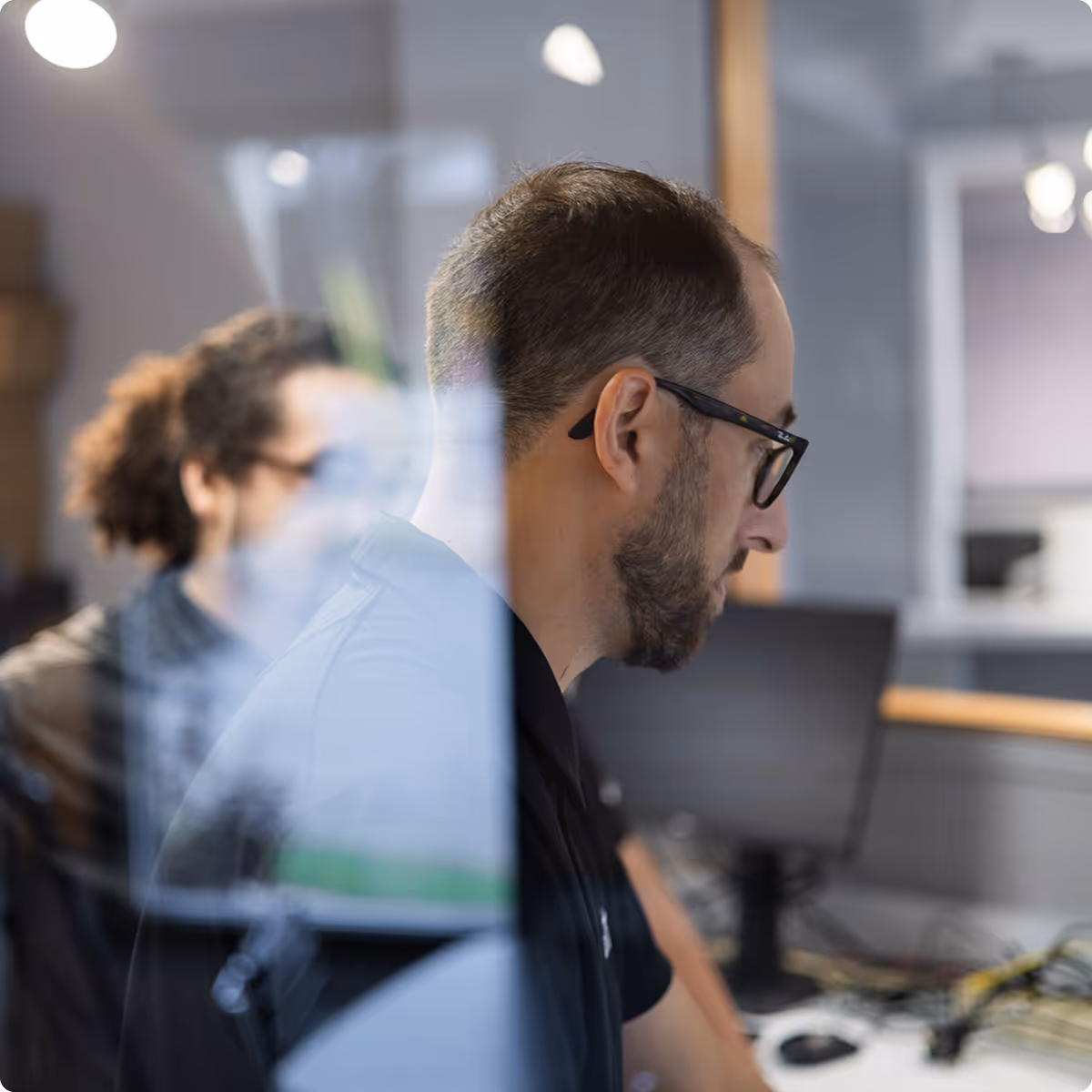 two Extra Mile technicians standing through a window and working together on a computer