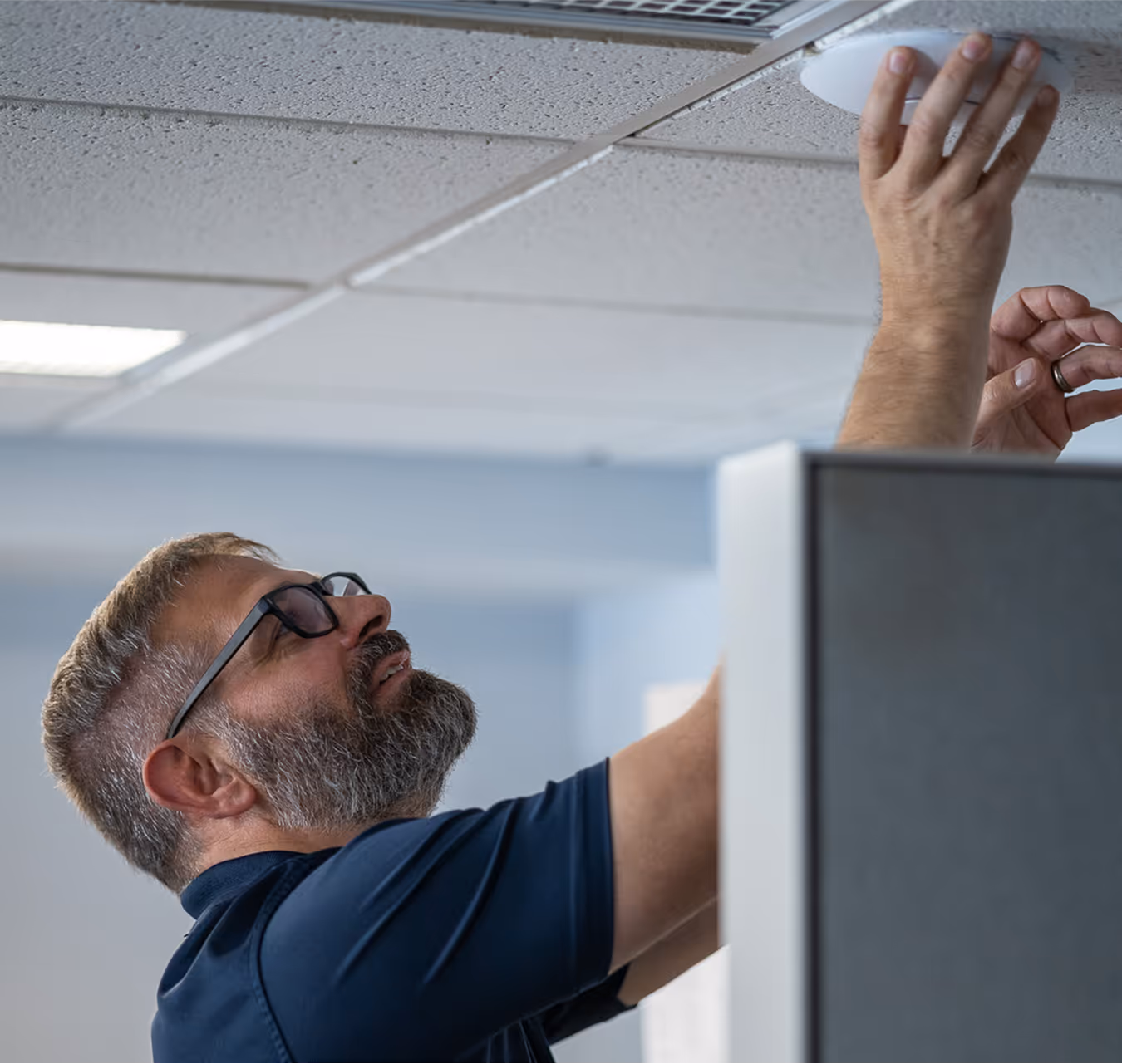 Owner Mike Davis installing an enterprise wifi device into the ceiling of a client's office