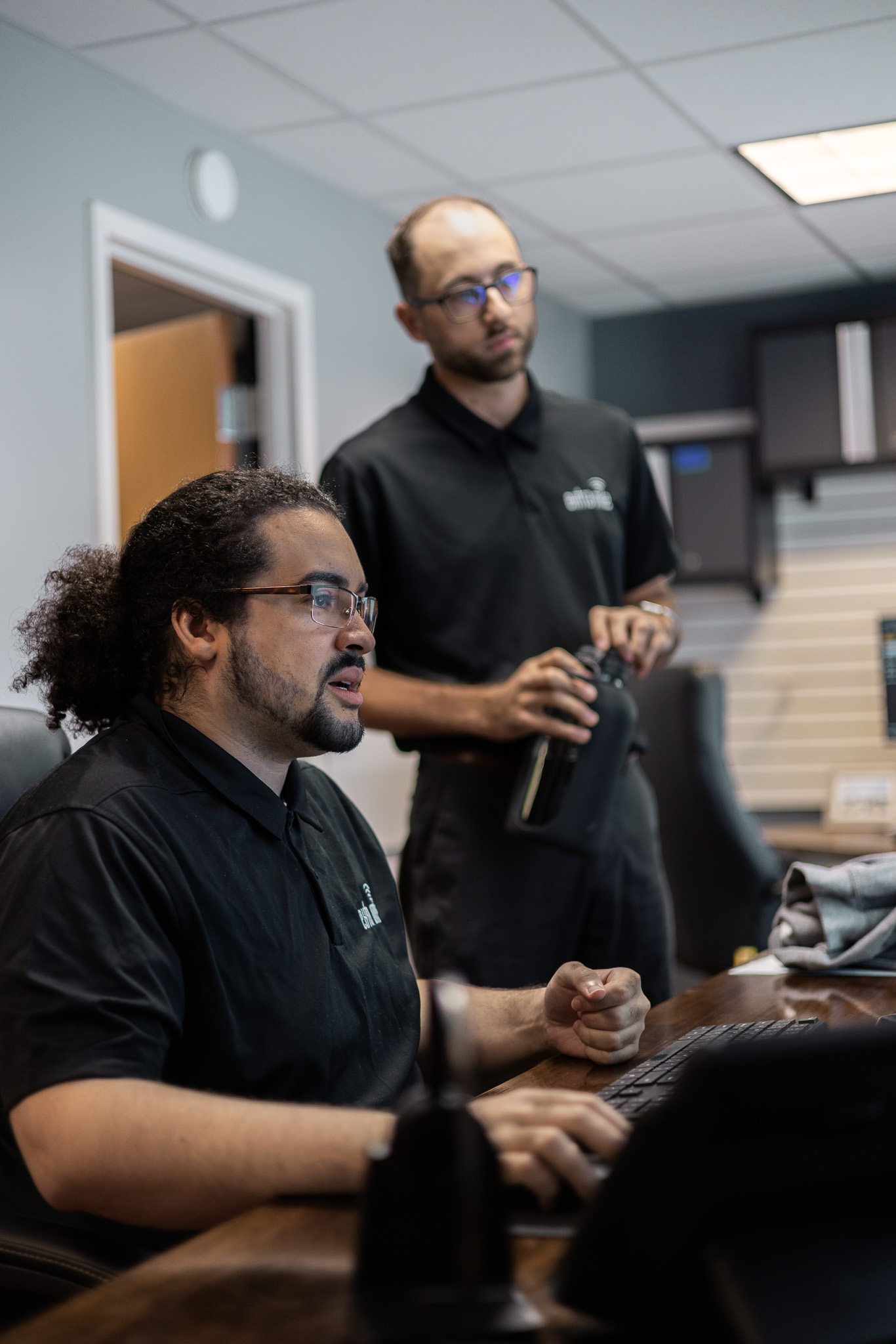 two Extra Mile technicians working together at a desk, looking at a computer