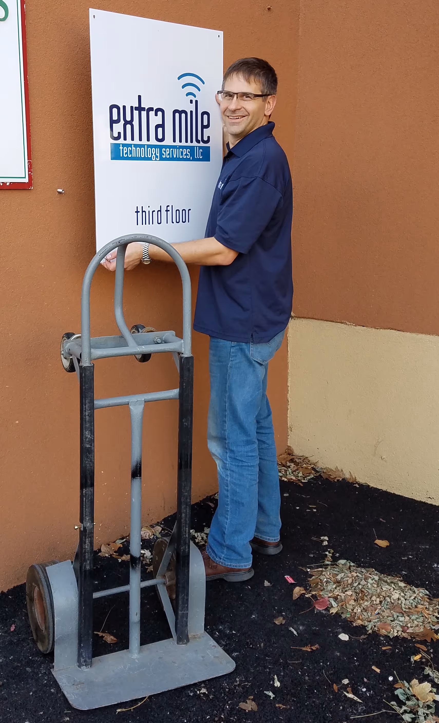 Extra Mile owner, Mike Davis, visibly younger and hanging up a sign for one of Extra Mile's very first office spaces