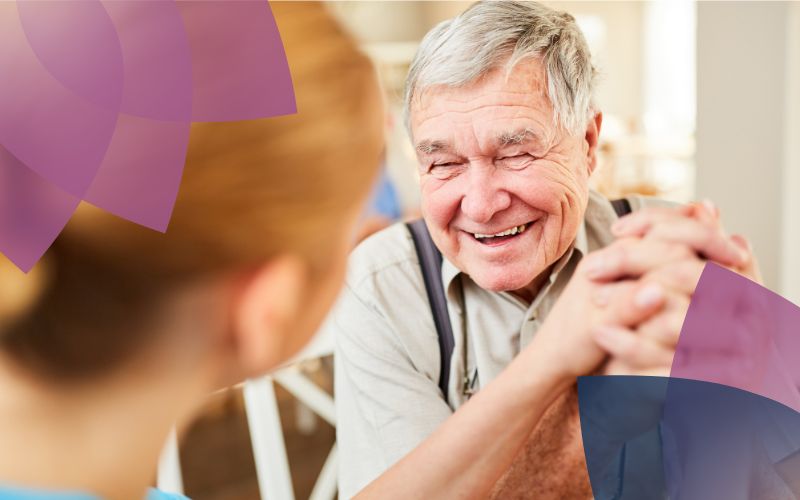 A support worker and an elderly participant share a joyful moment, smiling warmly at each other, radiating happiness and connection.