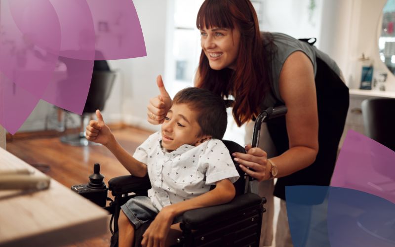An NDIS support worker and a participant in a wheelchair share a cheerful interaction, showcasing their strong rapport and highlighting the participant's engagement in a supportive and inclusive environment.