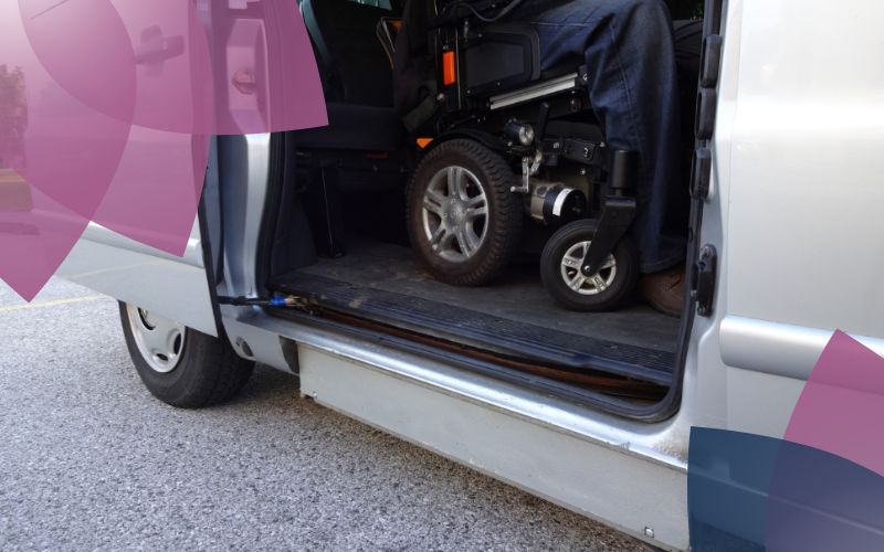 A participant in a wheelchair sits securely and comfortably in the back of a wheelchair-accessible van, ready to be carried out of the vehicle.