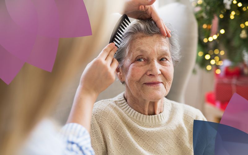 Elderly woman having her hair combed by support worker.
