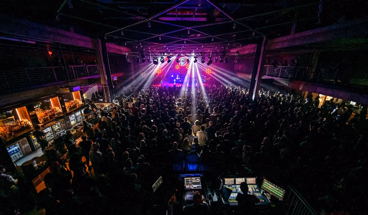 Crowded indoor concert venue at Tannahill’s Music Hall & Lounge with stage lighting beams over the audience and a DJ performing on stage.