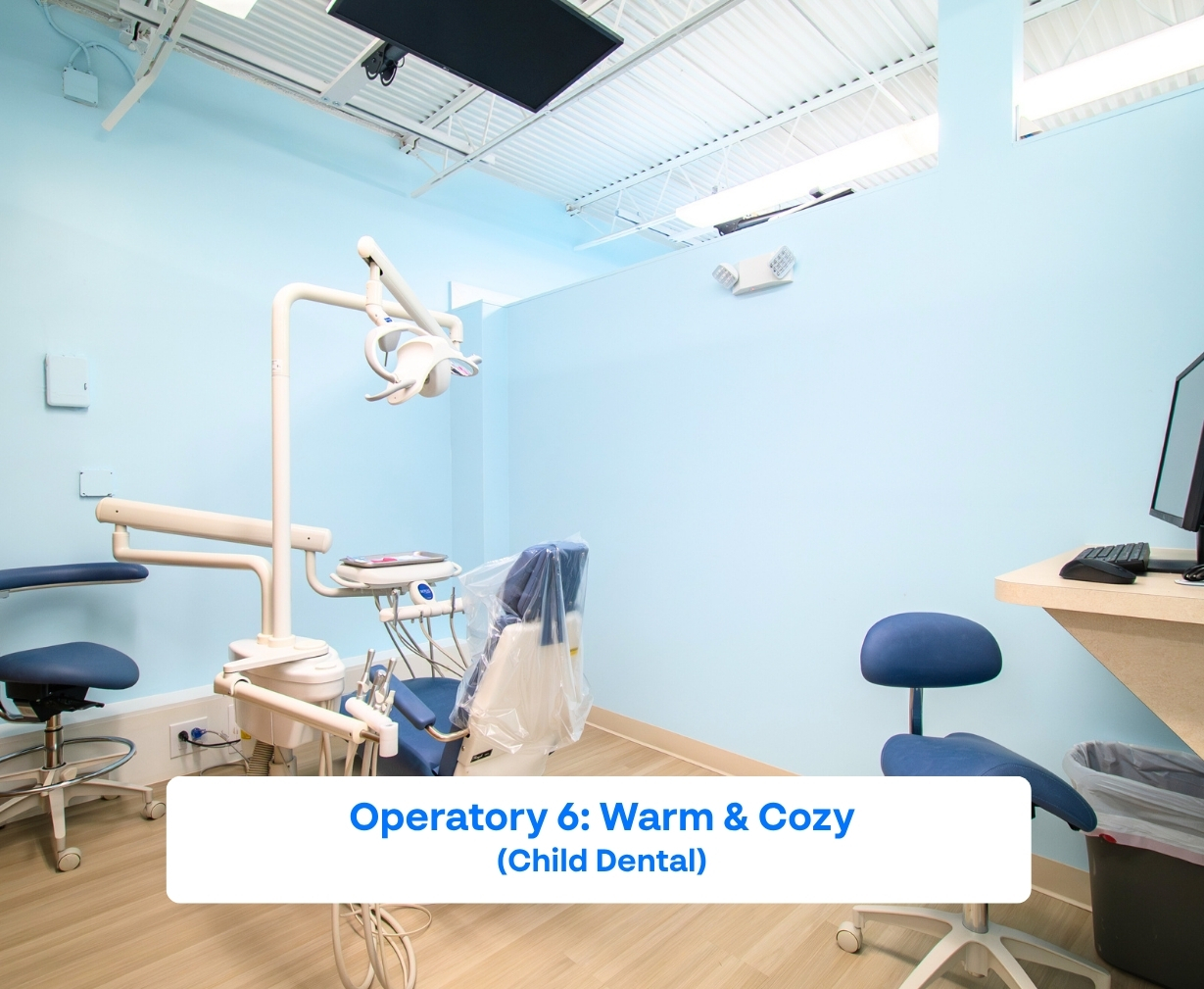 Bright pediatric dental operatory with blue walls, dental chair, stools, and overhead dental light.