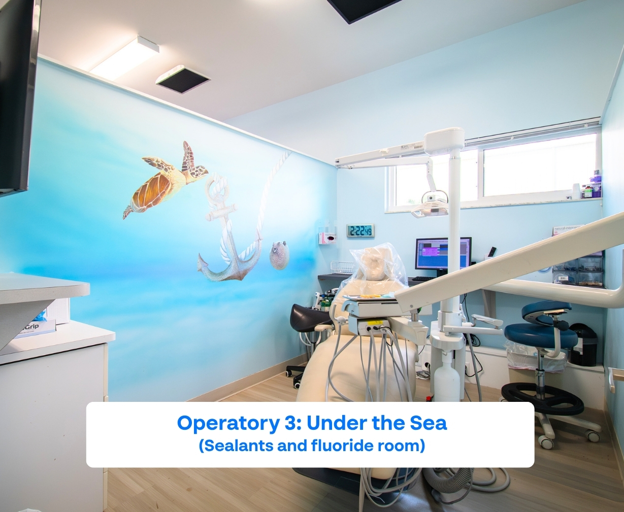 Bright pediatric dental operatory with sea life mural featuring a turtle, anchor, and pufferfish on light blue walls.