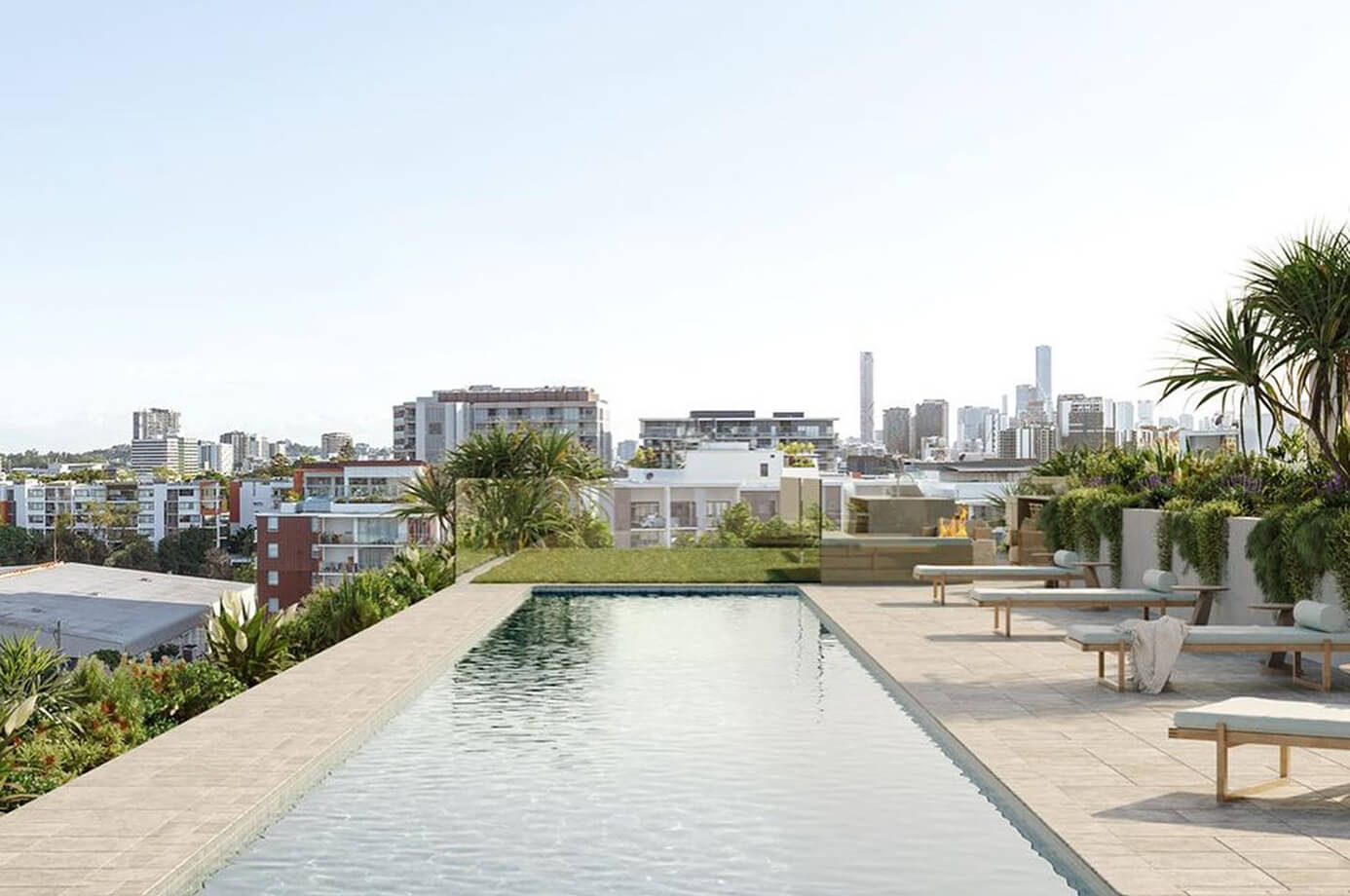 Rooftop pool overlooking a city skyline, surrounded by greenery and lounge chairs, under a clear blue sky.