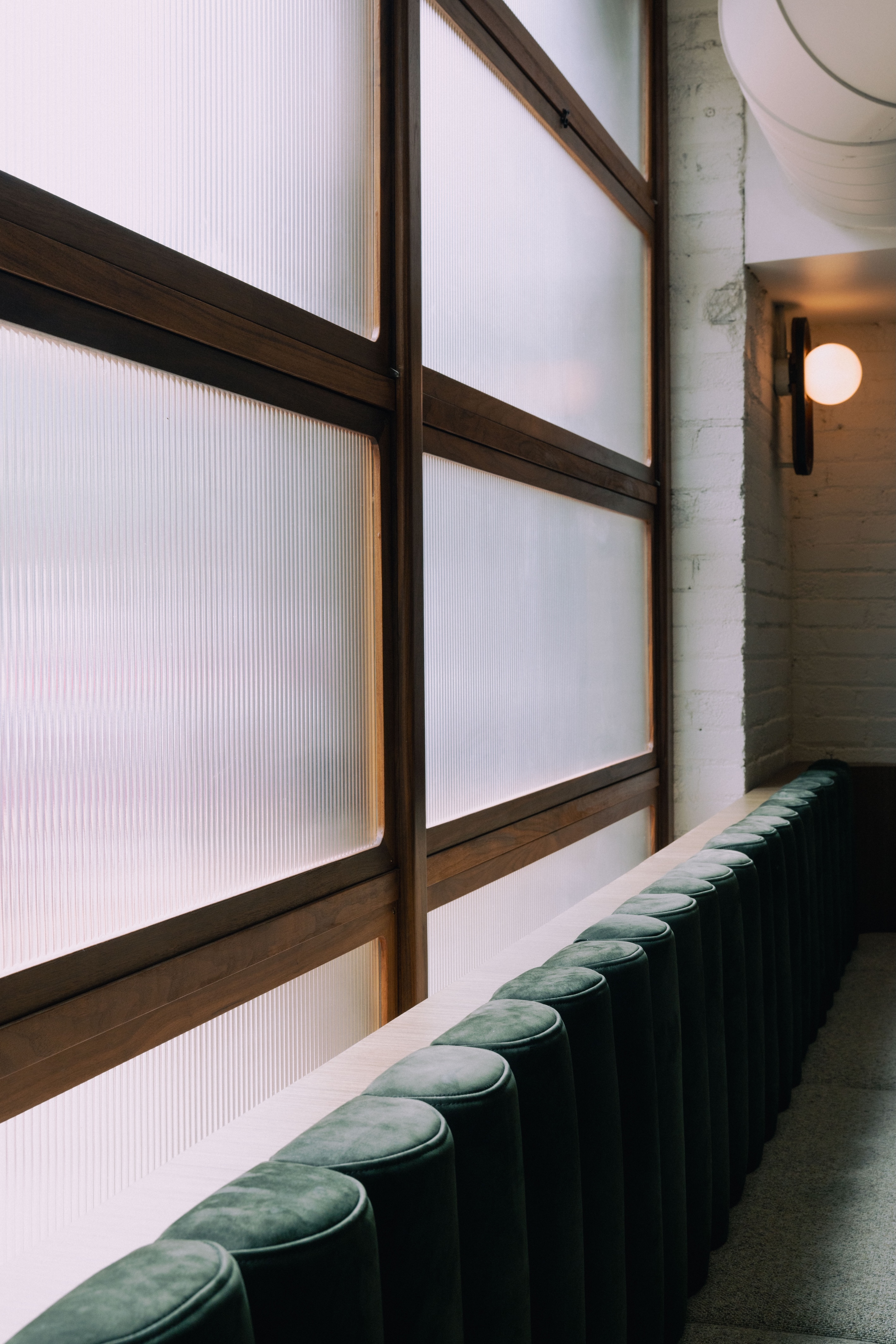 People sitting and conversing at a dimly lit restaurant table with vertical strip lights on the wall.