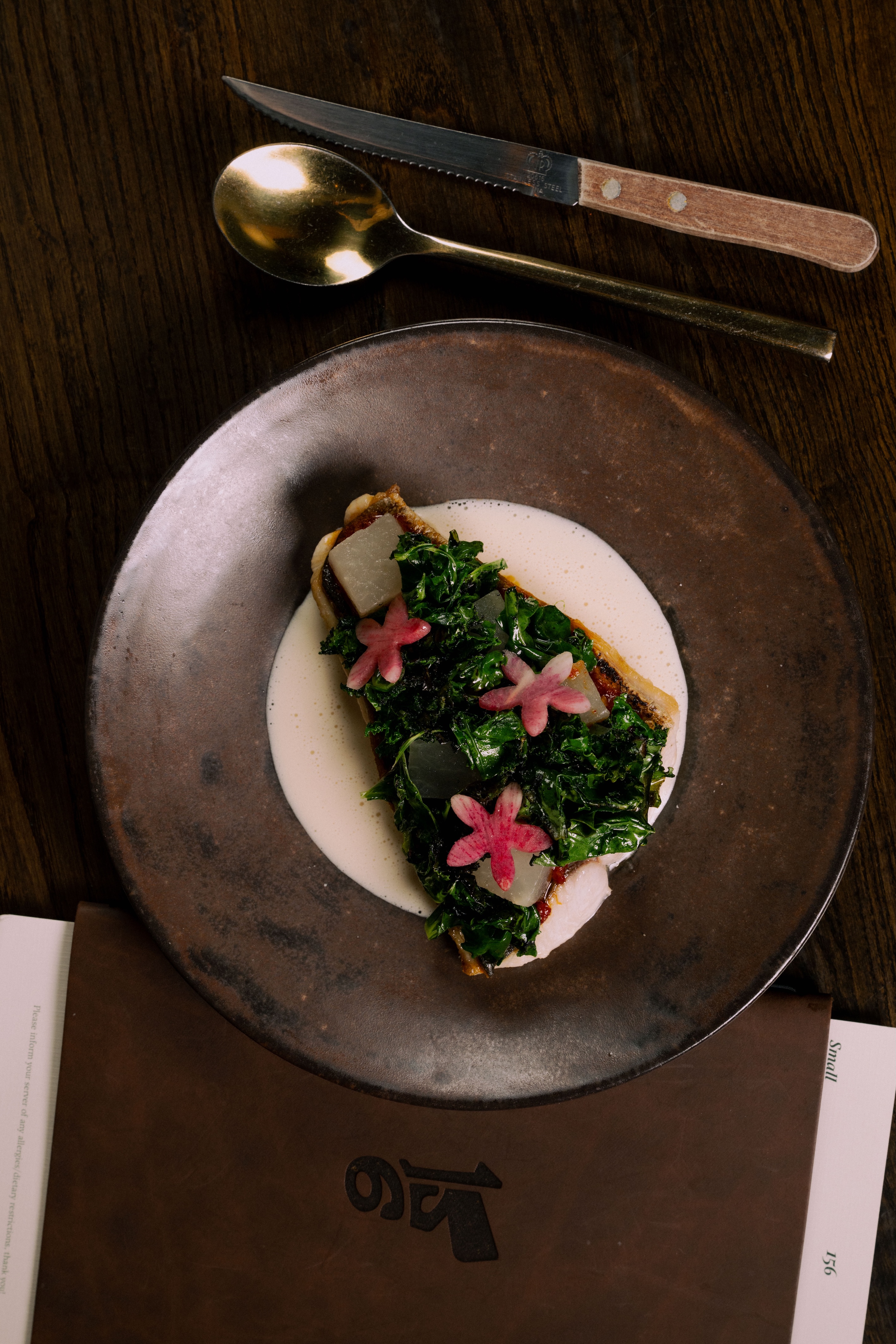 Four small appetizer bites, served on black pebbles in a white ceramic bowl.