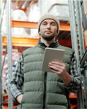 A man wearing a grey vest and a beanie holding a tablet.