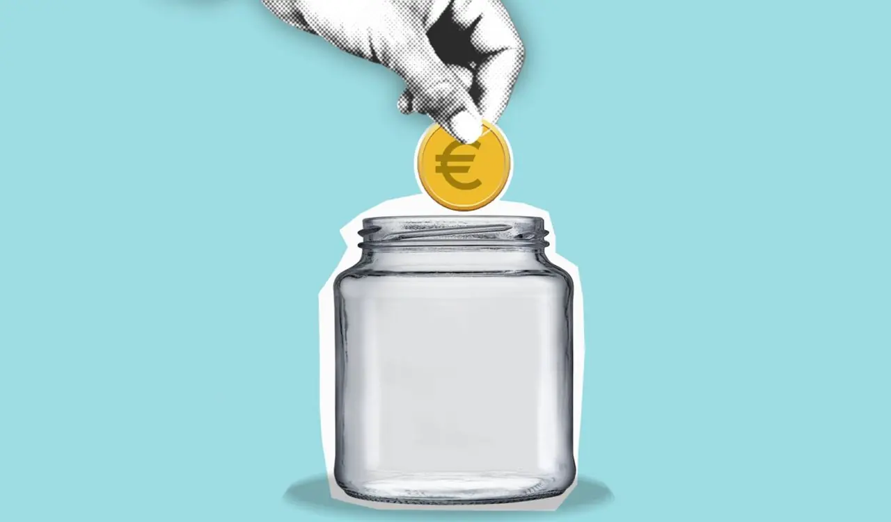 Hand wirft Münze in ein Sparglas als symbolisches Zeichen für Budgetplanung
