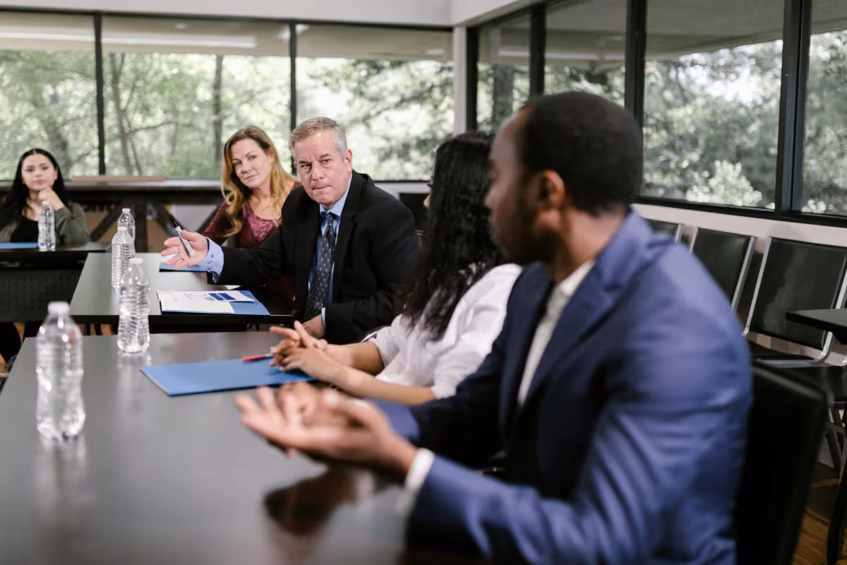 Five business professionals having a meeting around a table with laptops in a modern office.