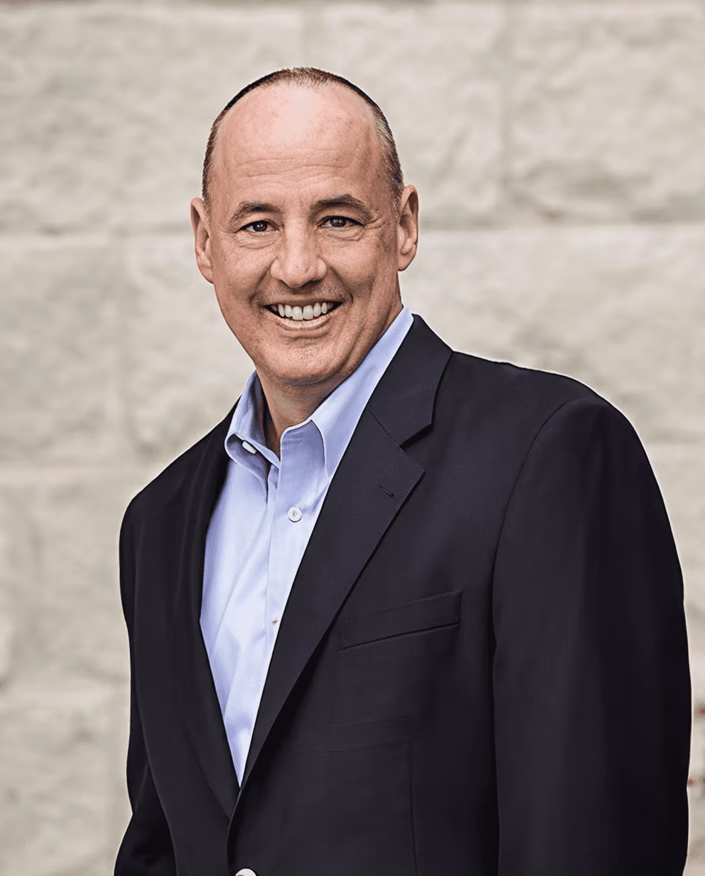Confident man in a suit and tie looking thoughtfully out of a window with a cityscape background.