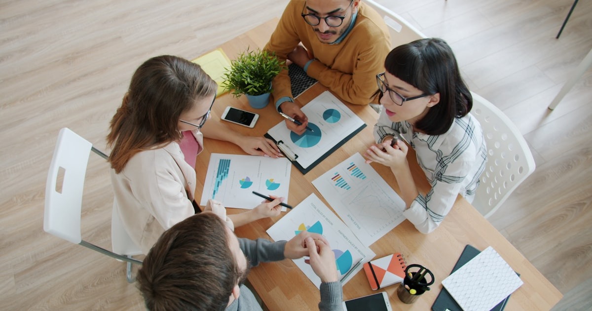A small startup team working through documents together around a table, the first real hires after a Series A round.