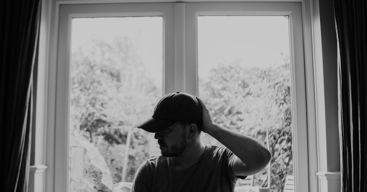 A startup founder sits in quiet reflection by a window, weighing a difficult leadership decision.