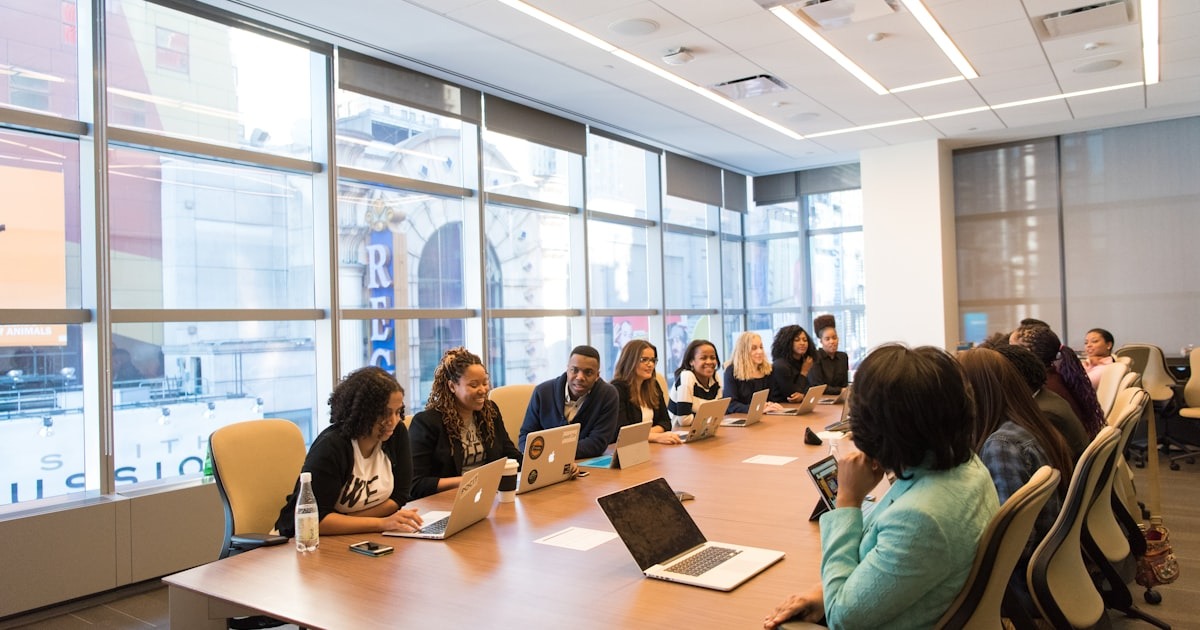 A diverse leadership team meeting around a conference table with laptops, where a first-time CEO learns to lead through others.