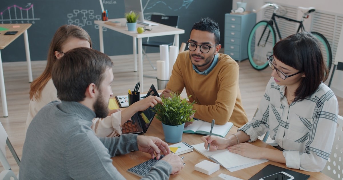 A diverse startup team collaborating around a table in a modern office during a growth phase