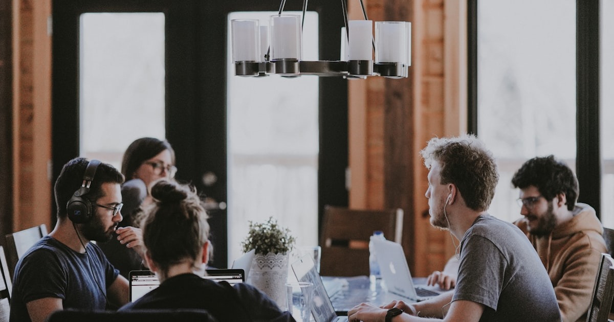 A founder in a candid working conversation with two others, the kind of outside perspective that names a reactive pattern before it hardens.