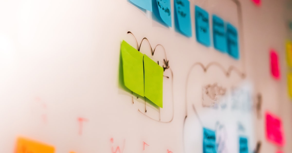 A wall densely covered with colorful sticky notes, each one a competing task, evoking the founder's struggle to tell what is genuinely urgent from what is merely loud.