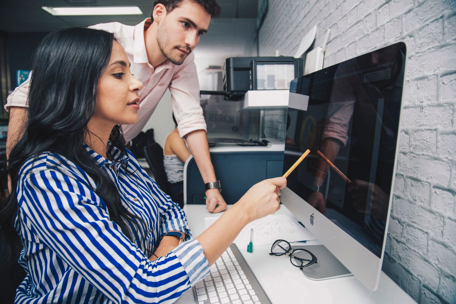 Two colleagues collaborate closely at a shared desk in a bright, modern office.