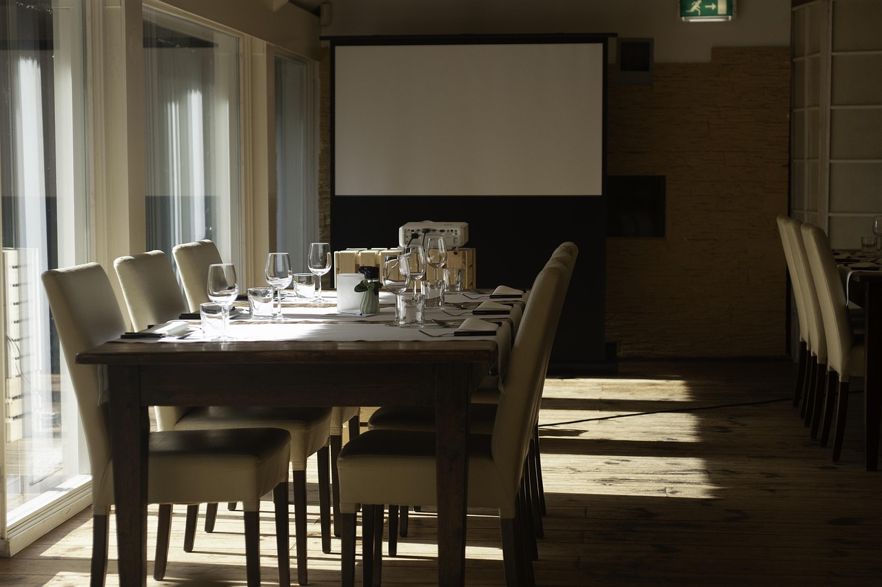 An empty formal boardroom set for a leadership meeting, with a projector screen at the front
