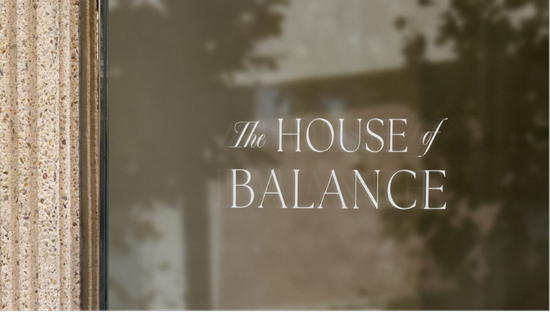 The House of Balance text displayed on a reflective glass surface next to a textured stone pillar.