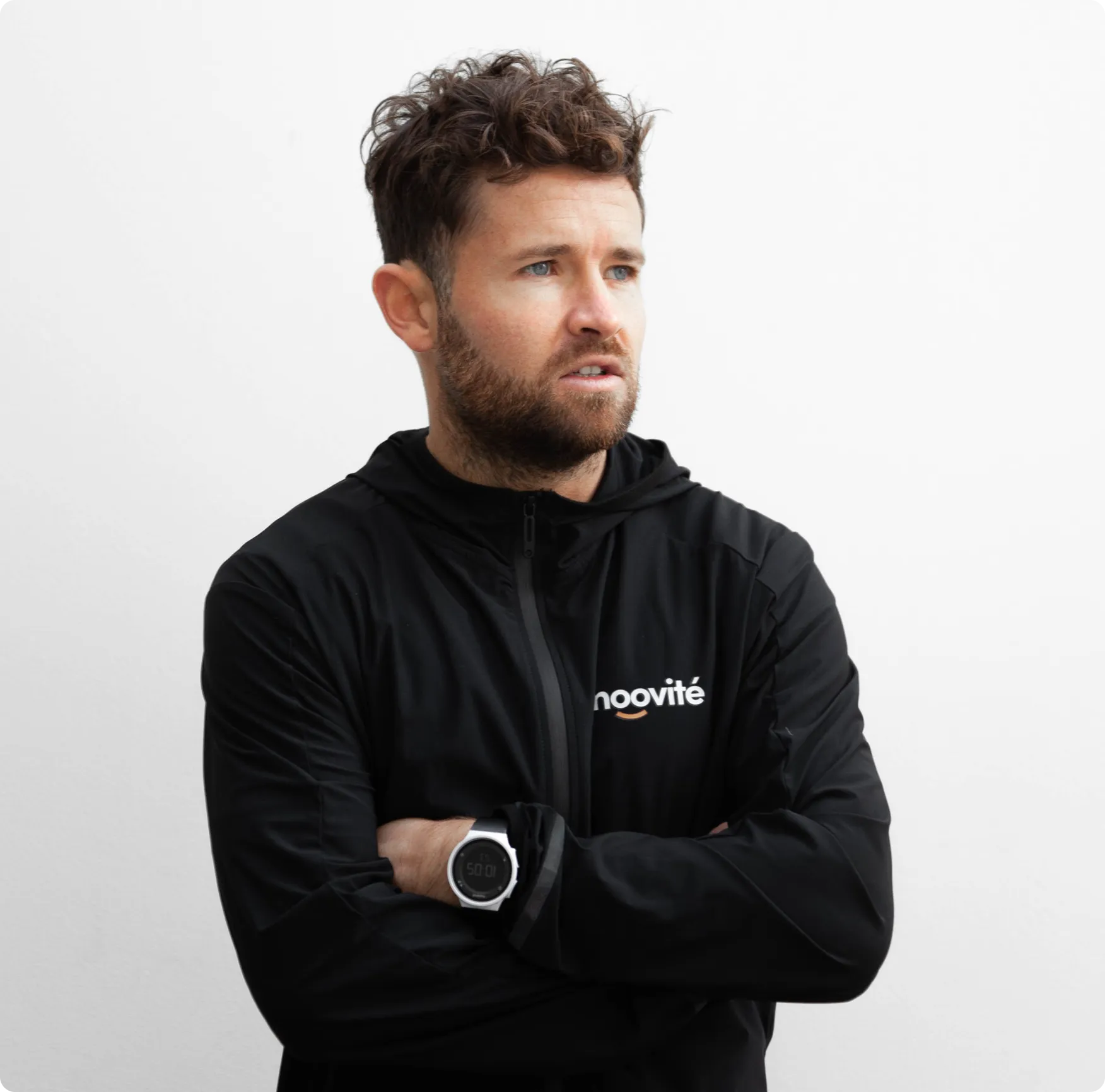 A man with his arms crossed wearing a black hoodie.