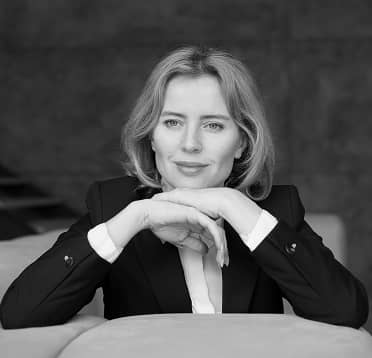 Black and white portrait of a confident woman in a suit resting her chin on her hands.