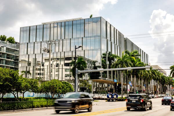 A large building with many reflecting glass panels near a busy roadway.