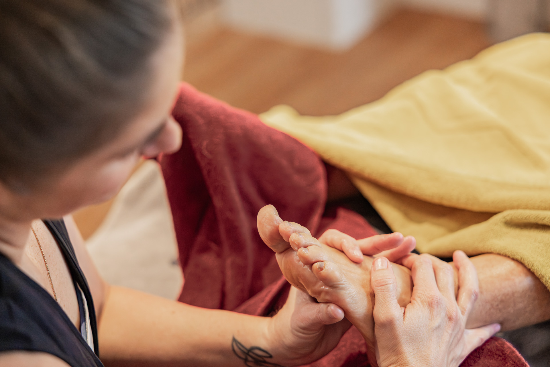 Masseurin Angela Hutter führt eine Fußreflexzonenmassage oder Fußmassage an einem Kunden durch. Detailaufnahme der therapeutischen Behandlung in der Praxis Hoch-Gefühl in Diepoldsau.