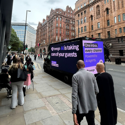 Digital billboard on a truck displaying AI service advertisement for managing guest interactions on a city street with pedestrians.