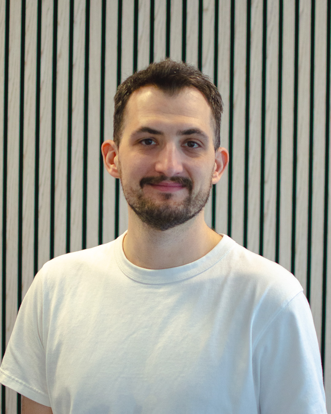 Man with glasses and beard wearing a light blue shirt crossing his arms and pointing both index fingers in opposite directions with a skeptical expression.