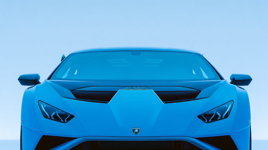 Front view of a blue Lamborghini sports car under clear blue sky.