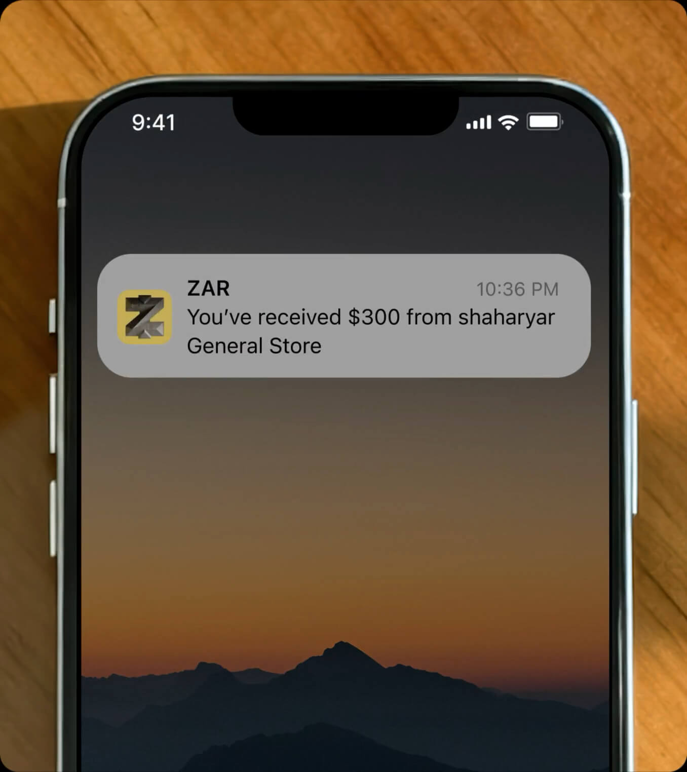 a phone with a notification from the Zar app that reads "you've received $300 from shaharyar General Store"