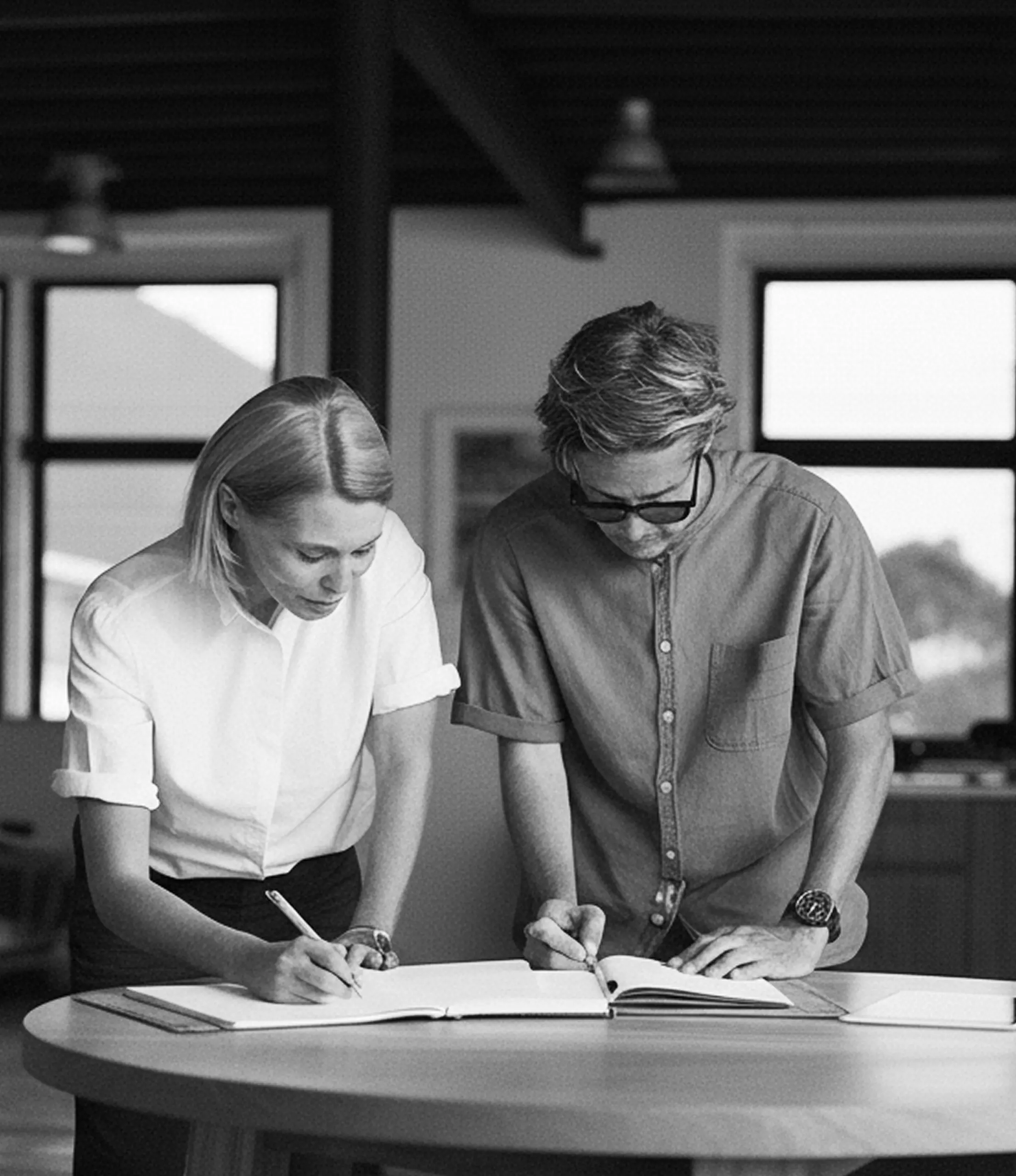 A man and woman going over office document on a standing table