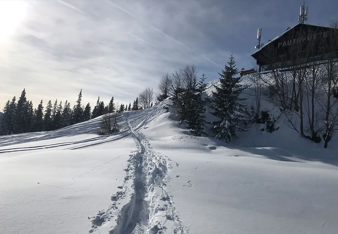 Verschneite Landschaft mit Fußspuren zur Leutascher Rauthhütte.