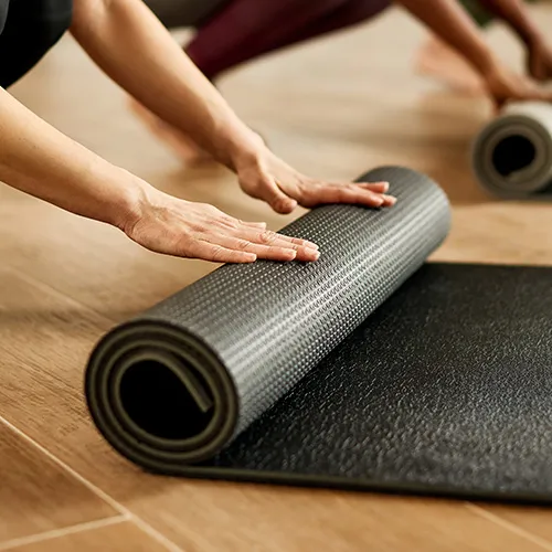 Schwarze Yogamatte wird aufgerollt.