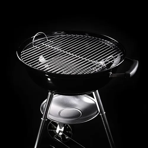 Schwarzer Holzkohlegrill vor dunklem Hintergrund.