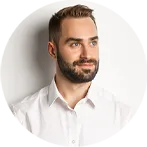 Bärtiger Mann in weißem Hemd vor hellem Hintergrund.