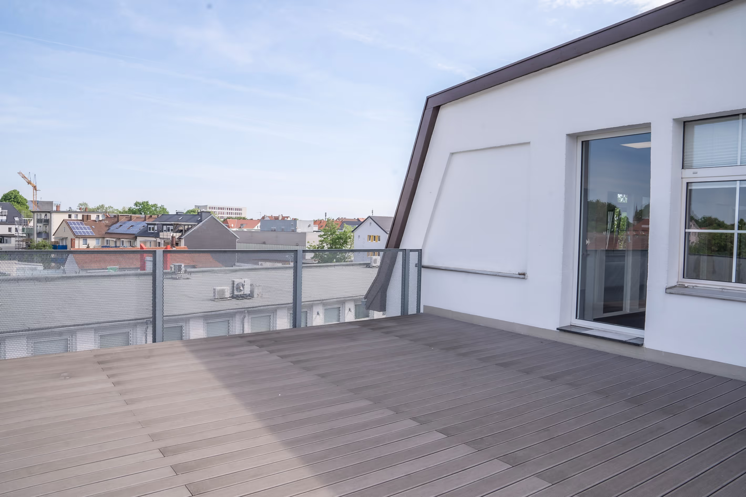 Moderne Dachterrasse des PG digital Büros mit Holzboden, Geländer und Blick über die Dächer von Bielefeld – ideal für Pausen oder Meetings im Freien.