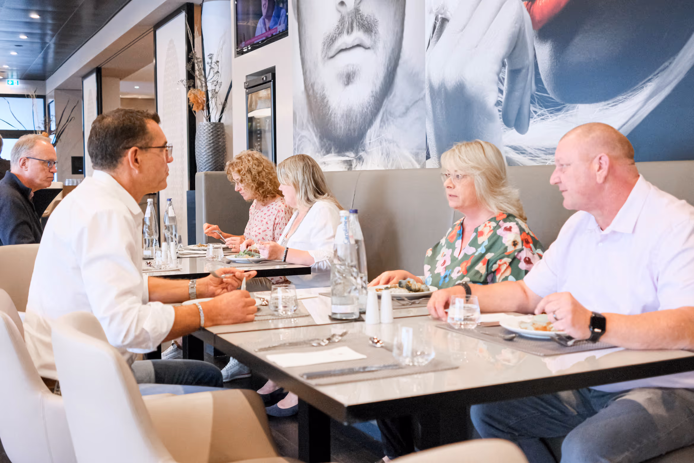 Teilnehmende des Steuerberater Digital Tags sitzen in einem modernen Restaurant an Tischen und essen gemeinsam. Die Atmosphäre wirkt entspannt und kommunikativ, im Hintergrund sind Wandbilder und Dekoration zu sehen.